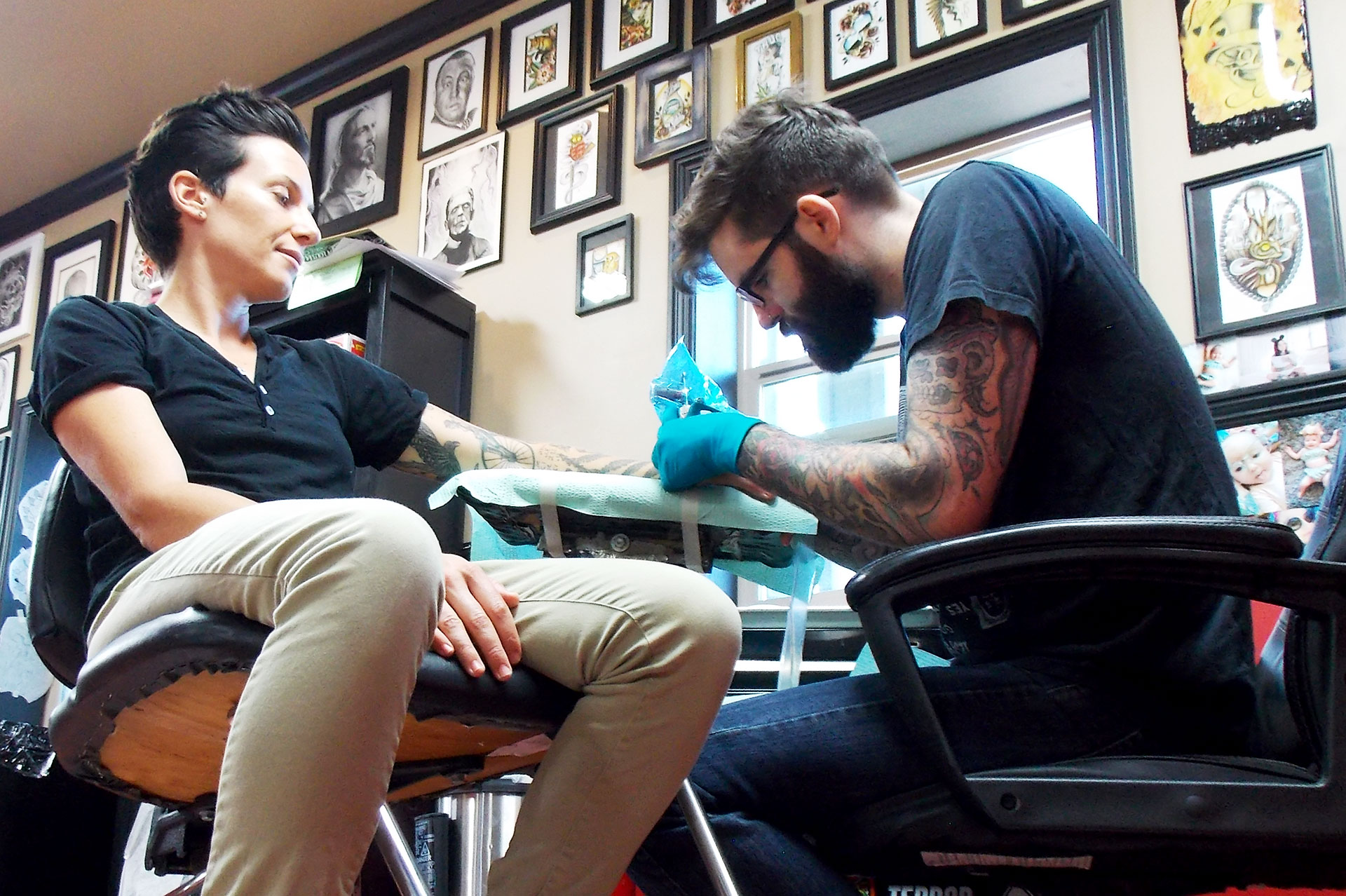 Tattoo Artist Jake Schroeder begins tattooing a finch on CEO and founder of Androgynous Fox clothing line, Renee Periat on Oct. 11 at Keith Duggan’s Ink Dynasty. Schroeder, originally from Paso Robles, began drawing tattoos in high school for his friends, and said he got “hooked” on them after he got his first tattoo: a pair of revolvers on his chest. The first tattoo he gave another person was a Queen Mary ship on a client’s leg. 